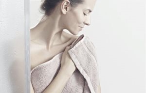 Een vrouw dept haar huid droog na het douchen.
