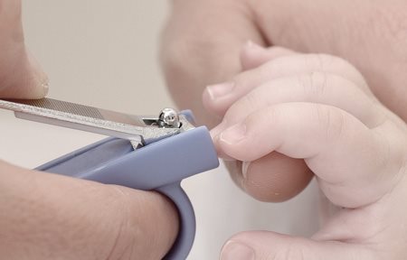 Een moeder knipt de nagels van een baby met een nagelknippertje.