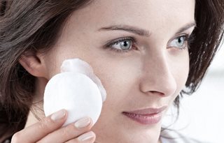 Vrouw brengt Reinigingsmelk aan op een wattenschijfje