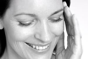 Een vrouw raakt haar gezicht aan met haar linkerhand.