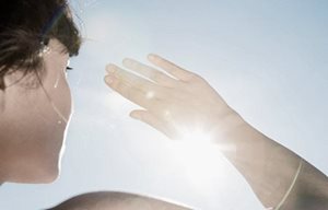 Een vrouw beschermt haar ogen tegen de zon met haar rechterhand.