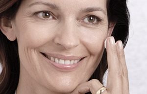 Een vrouw brengt crème aan op haar gezicht.