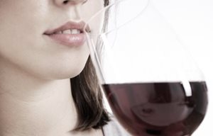 Een vrouw drinkt een glas rode wijn.