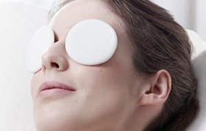 Een vrouw ontspant met oogpads op beide ogen.