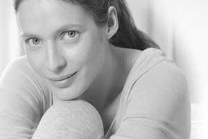 Een vrouw leunt met haar hoofd op haar knie.