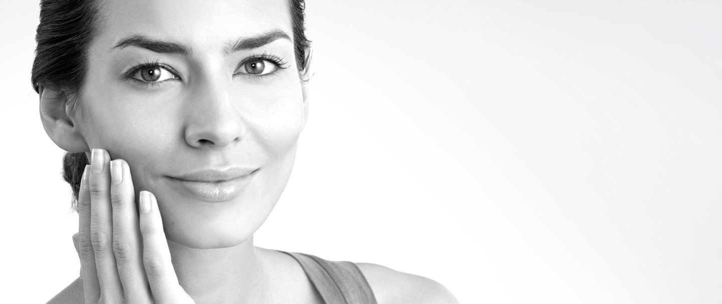 Een vrouw van middelbare leeftijd raakt haar rechterwang aan met de hand 