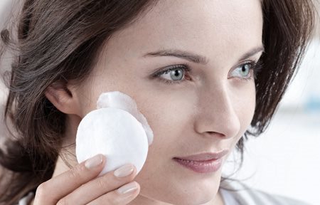 Een vrouw reinigt haar gezicht met een wattenschijfje