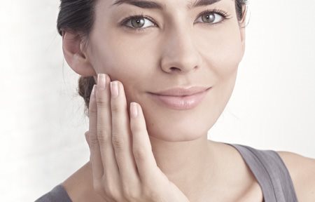 Een vrouw brengt crème aan op haar gezicht 